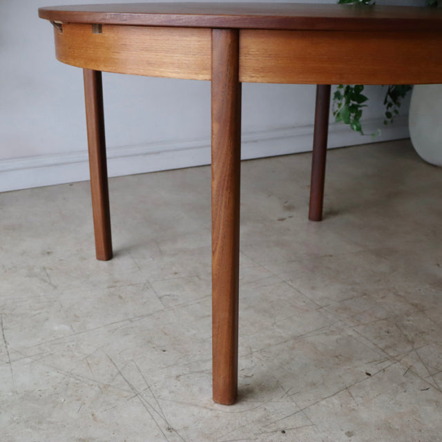 Mid-century British vintage teak dining table with round edges and tapered slender legs showing rich wood grain.