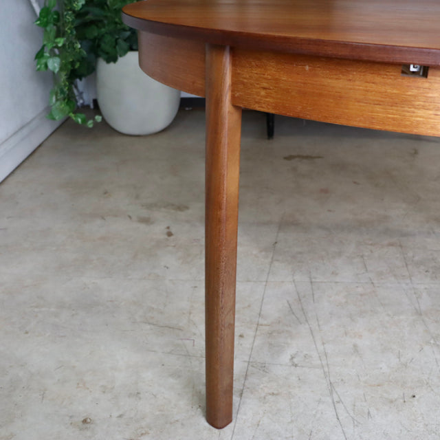 Mid-century vintage teak dining table leg with smooth cylindrical form and warm British wood grain finish.