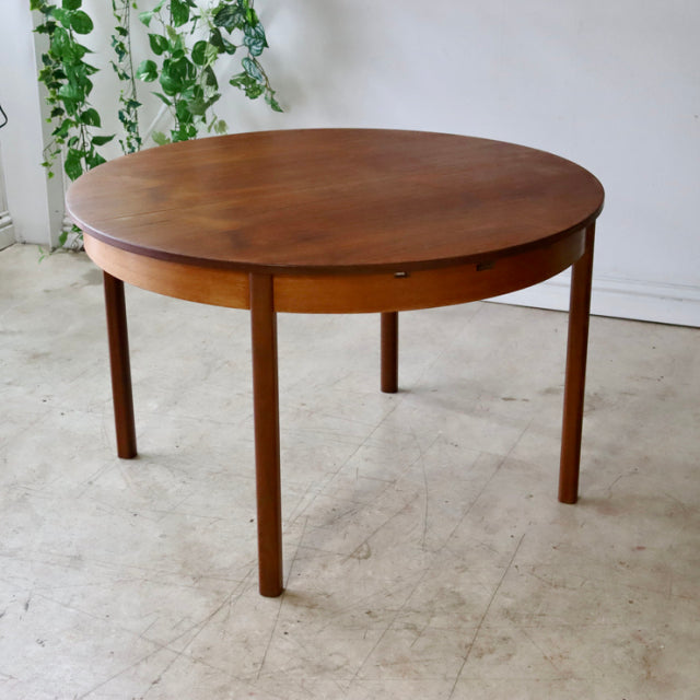 Vintage mid-century teak dining table with round top and slender straight legs, British-Denmark style.