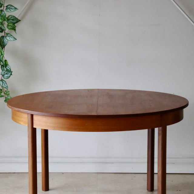 Mid-century vintage teak dining table with round top, clean wood grain, and slender British-style legs, Danish design.