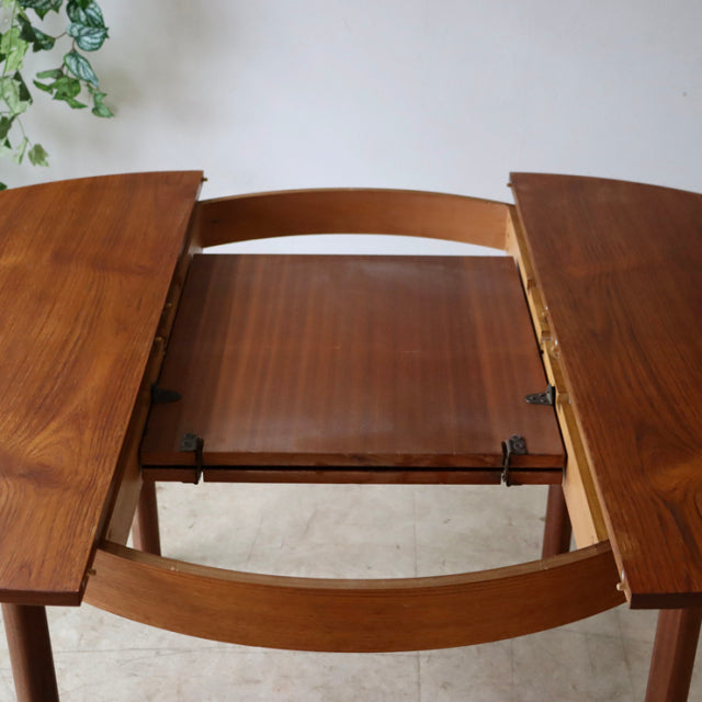 Vintage teak mid-century British dining table with extension, smooth wood grain and curved legs from Denmark.