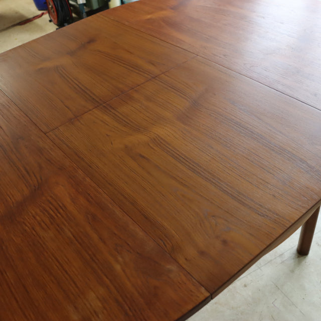 Mid-century British vintage teak dining table with rich wood grain and slender square legs.