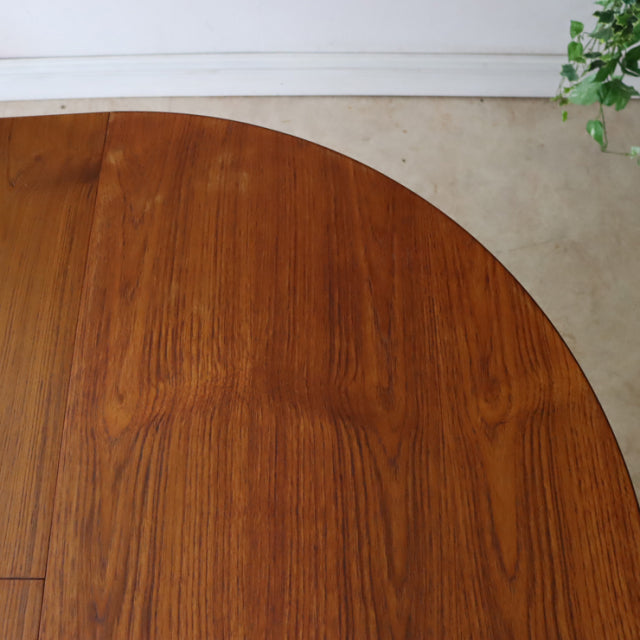 Round vintage teak dining table with rich wood grain, mid-century British design, smooth finish.