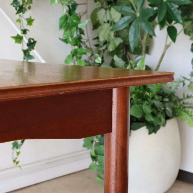 Close-up of vintage teak dining table corner with smooth mid-century British design and rich wood grain.