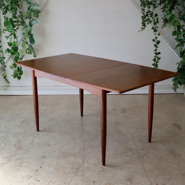 Vintage mid-century British teak dining table with rectangular top and tapered legs, showcasing rich wood grain and.