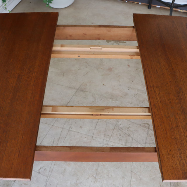 Vintage teak dining table with rich wood grain, mid-century British design featuring sturdy rectangular leaves and smooth.