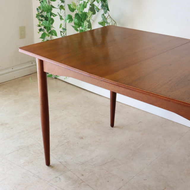 Mid-century British teak dining table with rich wood grain and tapered round legs in vintage Danish style.