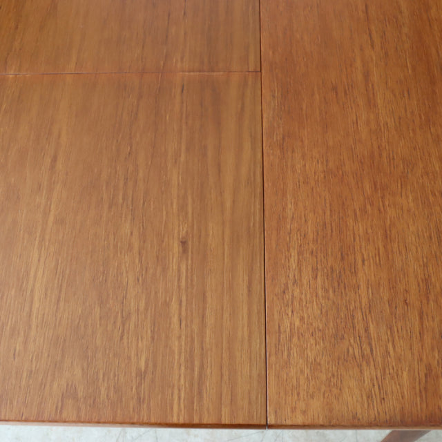 Mid-century British vintage teak dining table with oval top and visible wood grain details.