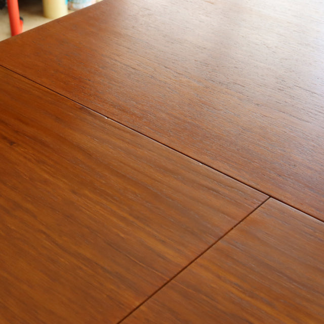Mid-century vintage teak dining table top with visible wood grain and smooth oval form from British-Danish design.