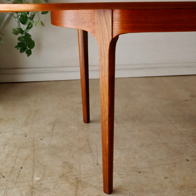 Mid-century British teak dining table leg with smooth wood grain and tapered design, vintage Danish style oval form.