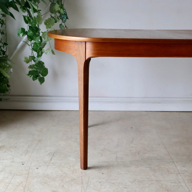 Vintage teak oval dining table leg with smooth grain, slender tapered British mid-century design.