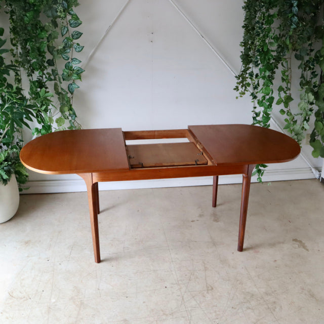 Vintage mid-century teak dining table by NATHAN, British design with oval top and tapered legs.