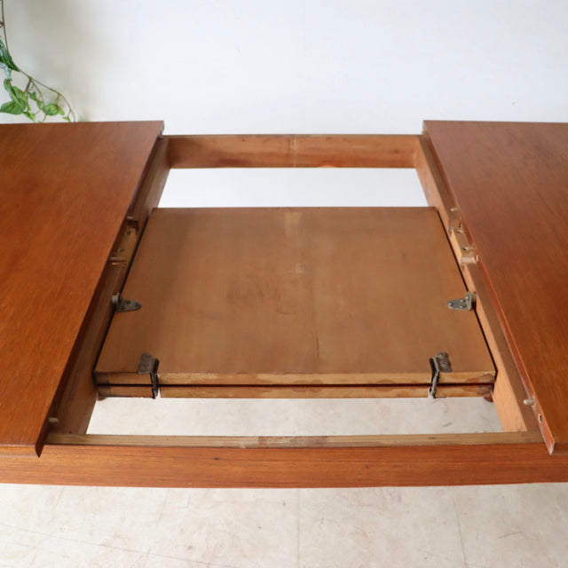 Vintage teak mid-century British Nathan oval dining table with extending leaf and rich wood grain.