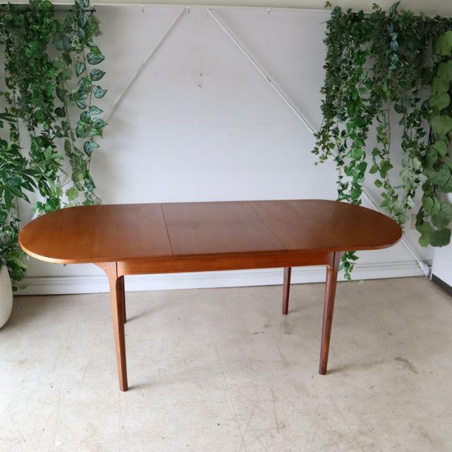 Mid-century British vintage teak dining table with oval top, smooth grain, and slender tapered legs.