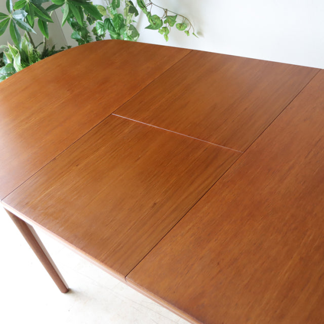 Oval vintage teak dining table with smooth wood grain, slender tapered legs, British mid-century Denmark design by NATHAN.