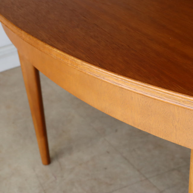 Vintage teak dining table by GREAVESandTHOMAS, British mid-century design with smooth oval top and tapered legs showing warm .