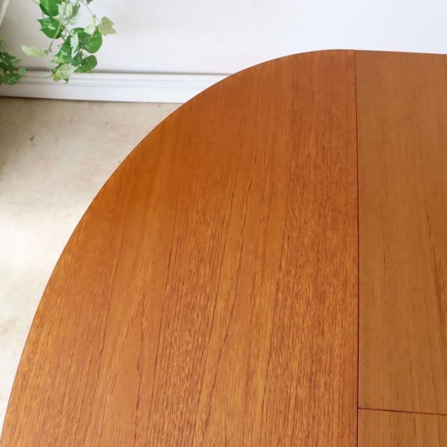 Mid-century British vintage teak dining table with oval top showcasing rich wood grain and slender legs from GREAVESandTHOMAS.