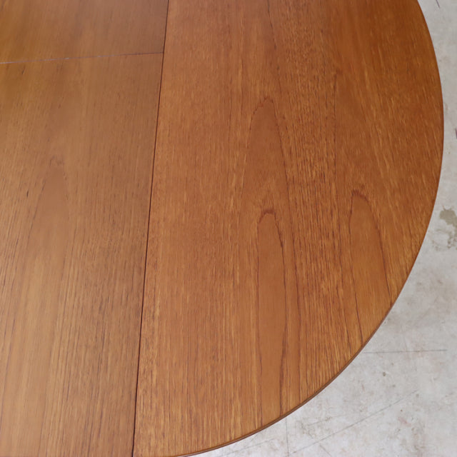 Vintage mid-century teak dining table with oval top showcasing warm wood grain, British and Danish design influence.