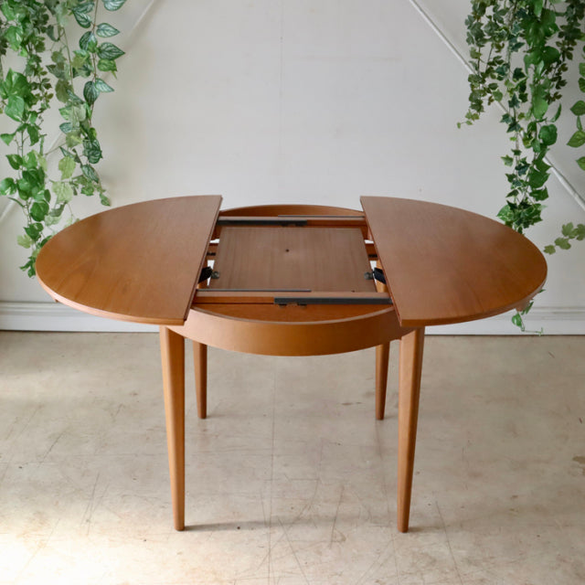 Vintage mid-century teak dining table by GREAVESandTHOMAS with oval top and rounded edges, featuring extendable leaves and.
