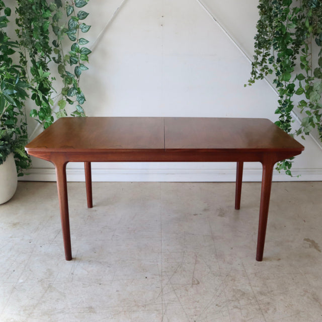Vintage mid-century McIntosh teak dining table with warm wood grain, rectangular top, and slender tapered legs from.