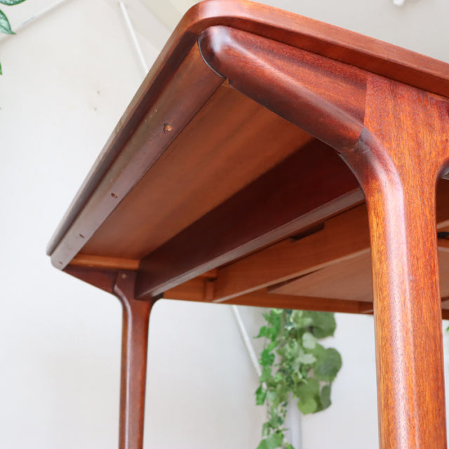 Mid-century British McIntosh teak dining table with rounded edges, visible wood grain, and slender tapered legs, vintage.