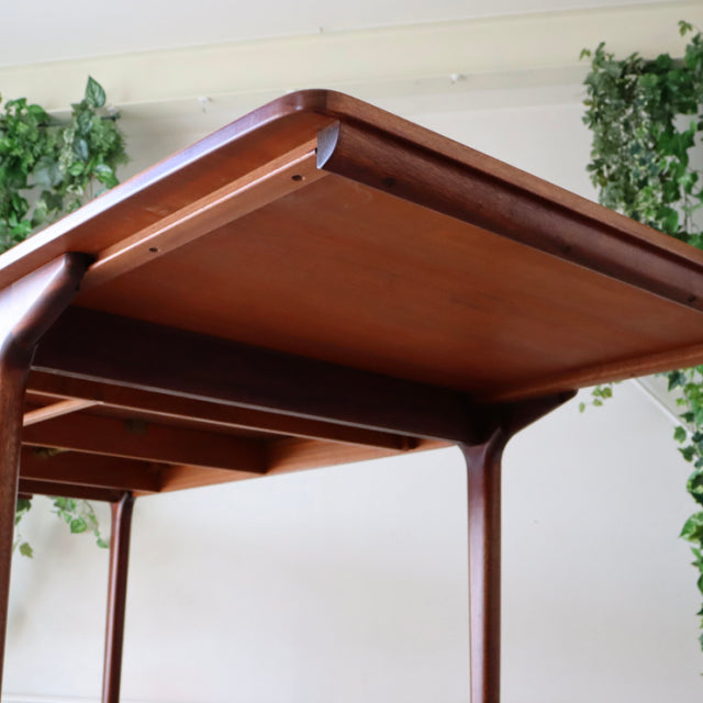 Vintage McIntosh teak dining table with smooth wood grain, rounded edges, and slender mid-century British legs.