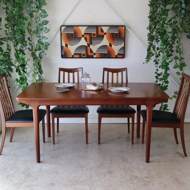 Vintage teak mid-century British McIntosh dining table with rounded edges and tapered legs, paired with matching wooden.