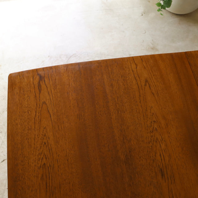 Vintage mid-century British teak dining table with rich wood grain and rounded edges.
