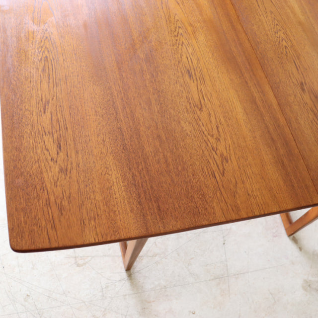Vintage mid-century British teak dining table with smooth wood grain and tapered legs, rectangular form.