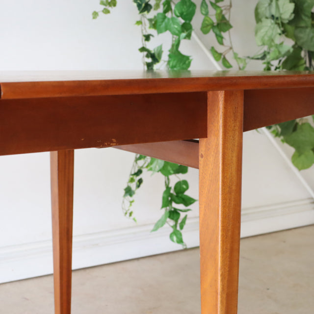 Mid-century British vintage teak dining table with rectangular top, clean lines, and tapered legs, showing smooth wood grain.