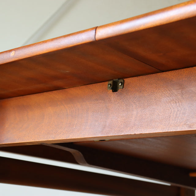 Close-up of mid-century British vintage teak dining table with smooth wood grain and brass hardware detail under rectangular .