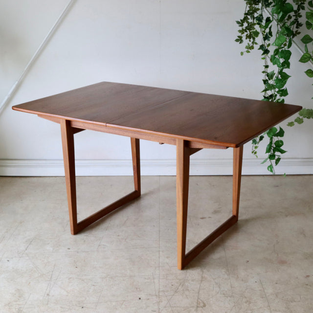 Vintage mid-century British teak dining table with rectangular top, angled legs, and smooth wood grain finish.