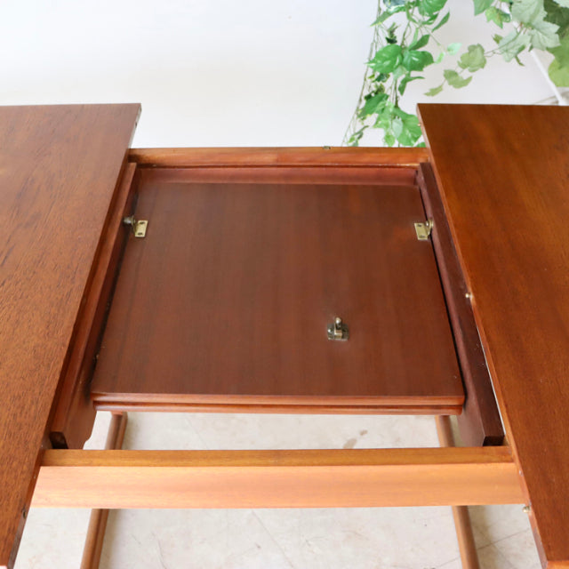 Mid-century British vintage teak dining table with extending top, showcasing rich wood grain and sturdy legs.