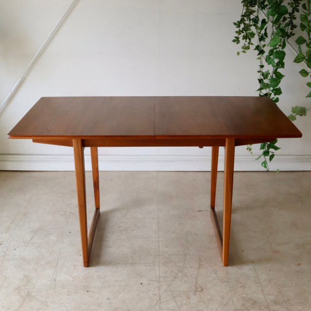 Mid-century British vintage teak dining table with rectangular top and straight, angular legs, showcasing rich wood grain.