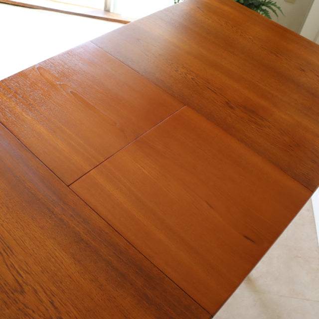 Mid-century British teak dining table with rich wood grain and clean rectangular form, vintage Denmark style legs visible at .