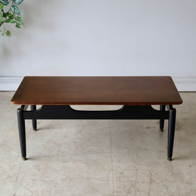 Vintage British G-Plan mid-century teak coffee table with smooth wood grain and black tapered legs.