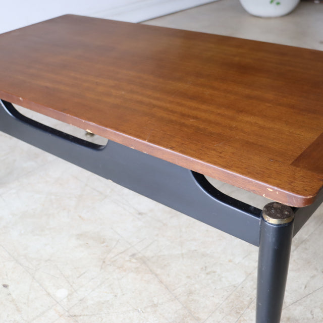 Vintage G-plan mid-century British teak coffee table with black tapered legs and visible wood grain.