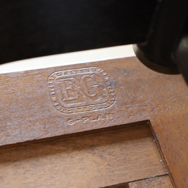 Close-up of vintage British G-Plan teak coffee table corner showcasing wood grain and embossed mid-century brand logo.
