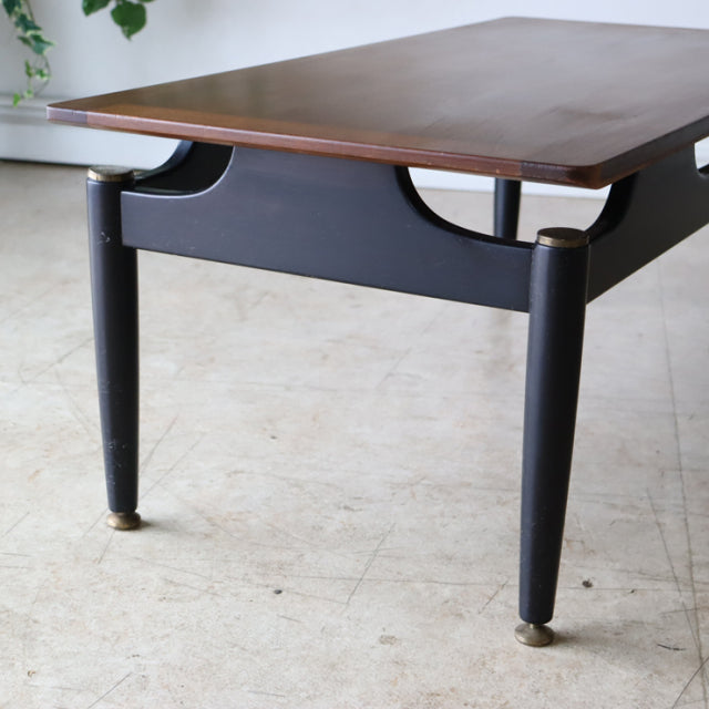 Vintage British mid-century G-Plan teak coffee table with black tapered legs and brass-capped feet, smooth wood grain top.