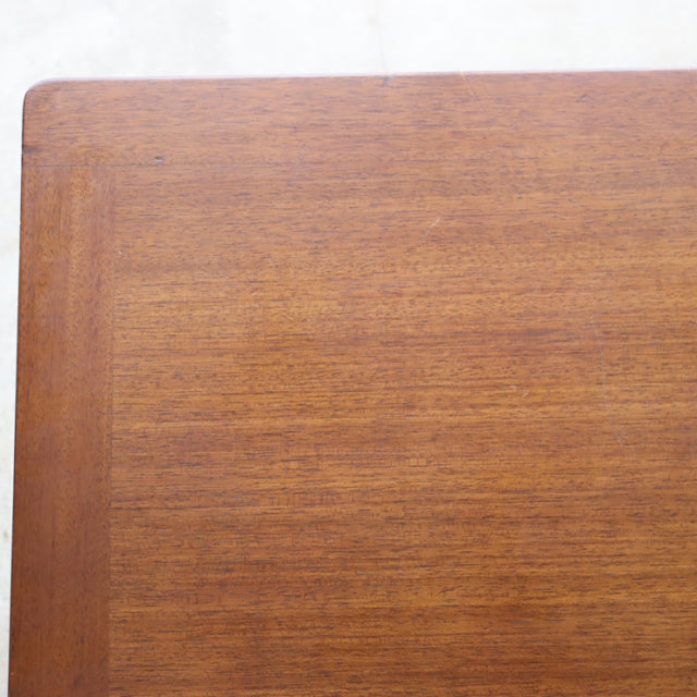 Close-up of vintage British G-plan teak coffee table corner, showcasing smooth wood grain and mid-century Denmark design.