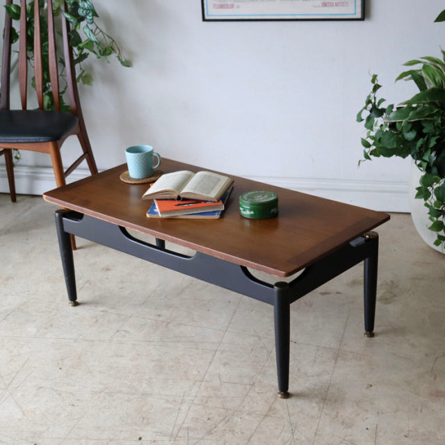 Vintage British G-plan mid-century teak coffee table with black tapered legs, visible wood grain, and rectangular top.