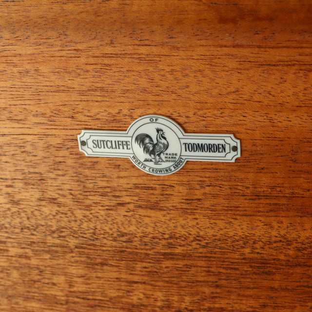 Close-up of vintage teak wood grain with oval Sutcliffe of Todmorden British mid-century Denmark brand label.