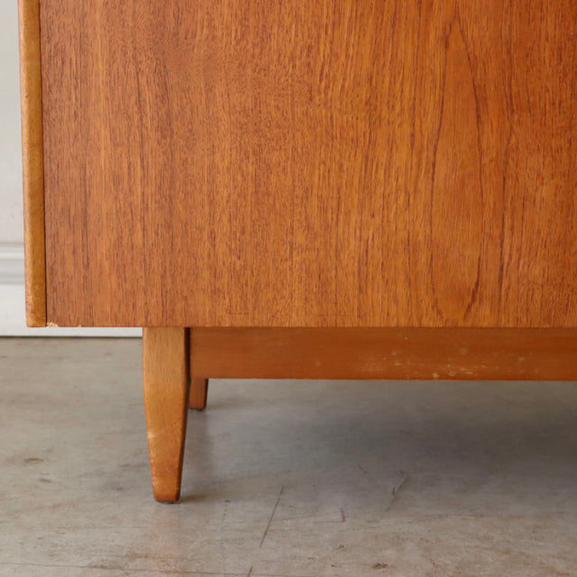 Close-up of vintage teak storage box leg showing warm wood grain and tapered mid-century British design by Sutcliffe of.