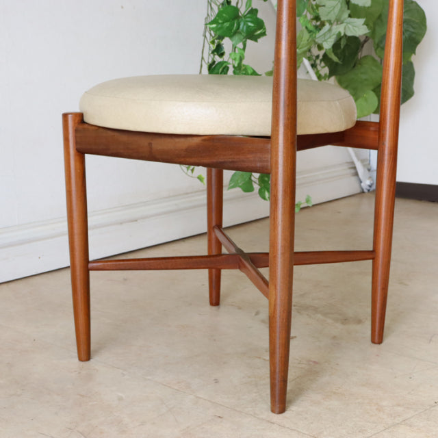 Set of four vintage G-Plan mid-century teak dining chairs with rounded beige upholstered seats and slender tapered legs.
