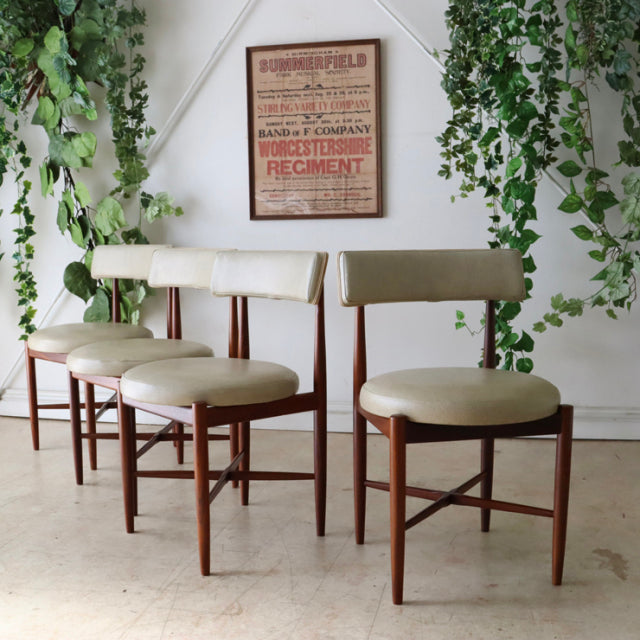 Set of four vintage G-Plan mid-century teak dining chairs with cream vinyl seats and backrests, sleek tapered legs, and.