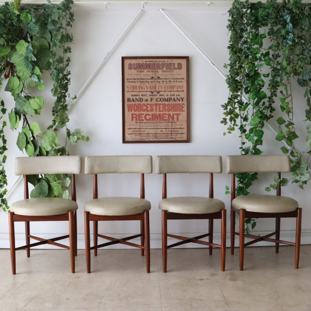 Set of four vintage teak G-plan dining chairs with British mid-century design, tapered legs, and beige upholstered seats,.