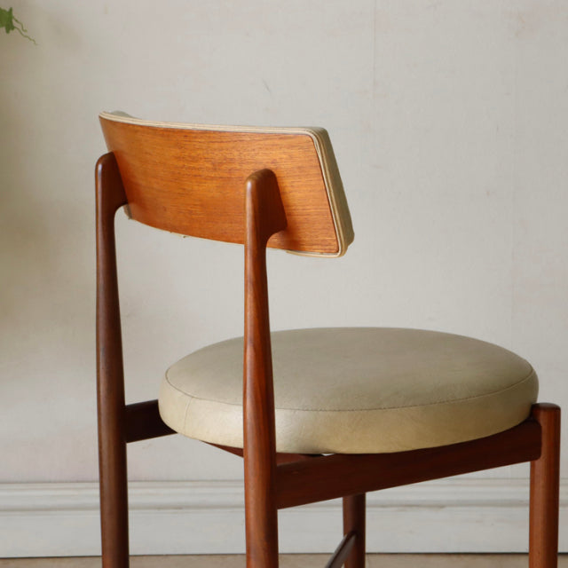 Set of four vintage G-plan teak dining chairs from mid-century British design with curved plank backrests and beige.
