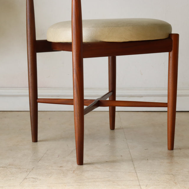 Set of four British vintage mid-century teak dining chairs by G-Plan with beige upholstered seats and slender tapered legs.