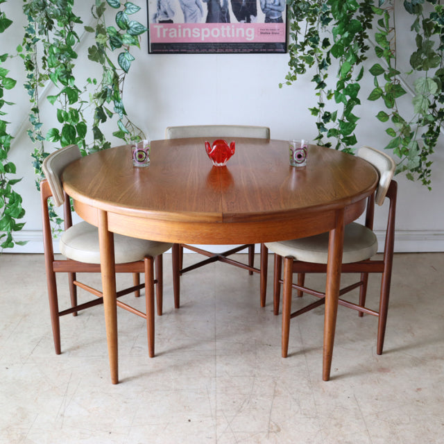 Vintage teak G-Plan mid-century British dining table with rounded top and slender tapered legs, paired with four matching.