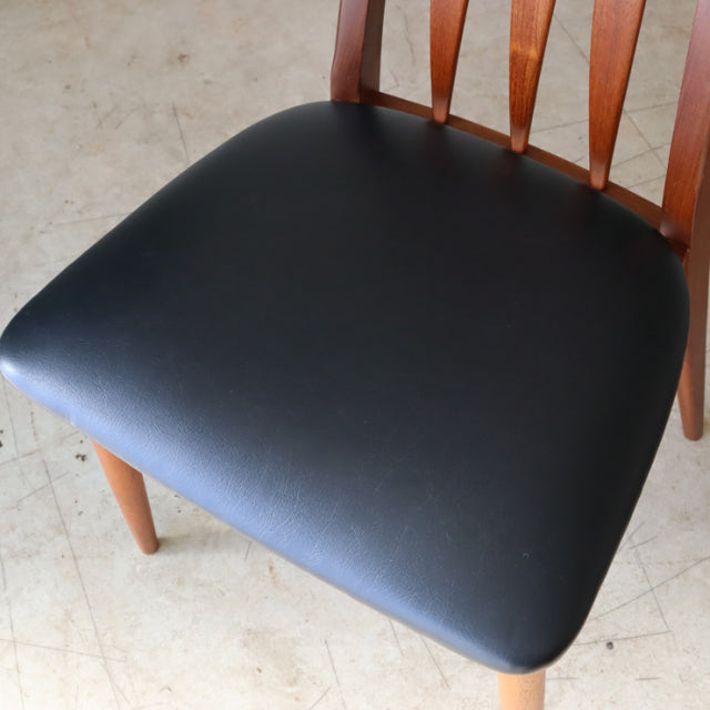 Mid-century Danish vintage dining chair with teak frame and smooth black leather seat cushion, tapered legs, and curved.